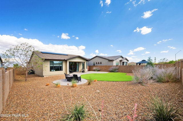 rear view of house featuring solar panels, a patio area, and a lawn