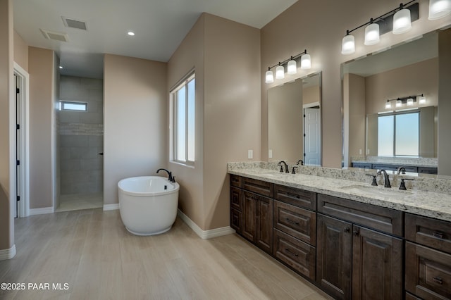 1438 W Anne Marie Dr, Chino Valley, AZ 86323 - bathroom featuring healthy amount of natural light, a soaking tub, double vanity, and wood finished floors