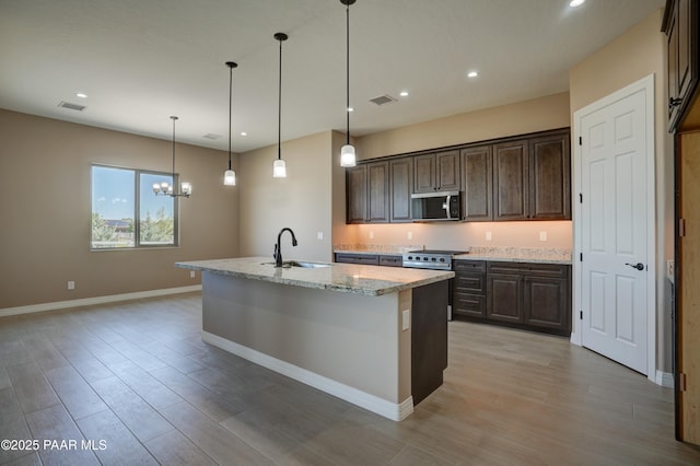 1438 W Anne Marie Dr, Chino Valley, AZ 86323 - kitchen featuring stainless steel microwave, dark brown cabinetry, light wood-style floors, light stone counters, and recessed lighting
