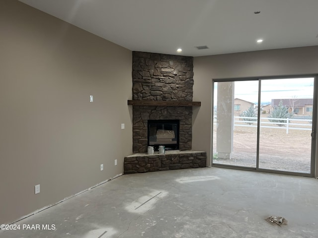 unfurnished living room featuring a stone fireplace and concrete flooring