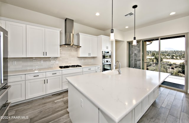kitchen with a sink, black gas stovetop, double oven, wall chimney range hood, and visible vents