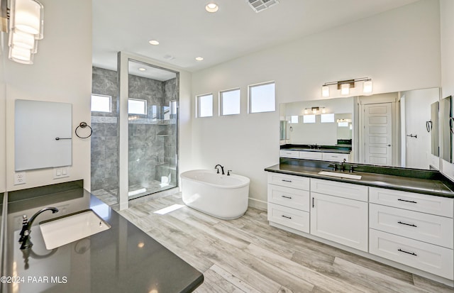 full bath featuring a soaking tub, wood finished floors, a sink, and walk in shower