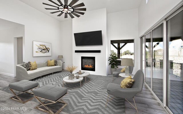 living room with a high ceiling, wood finished floors, and a glass covered fireplace