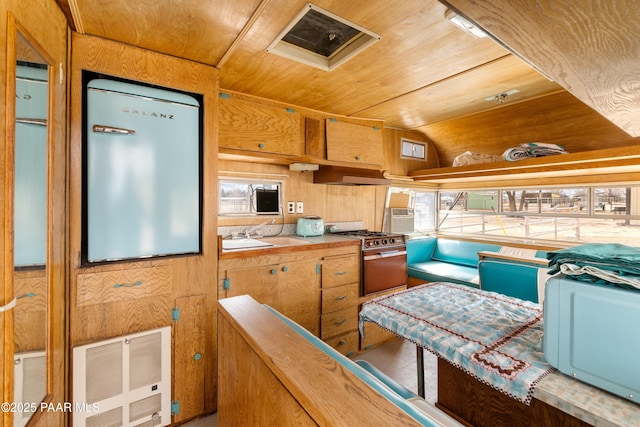 kitchen featuring stainless steel range, under cabinet range hood, a sink, wooden ceiling, and a healthy amount of sunlight