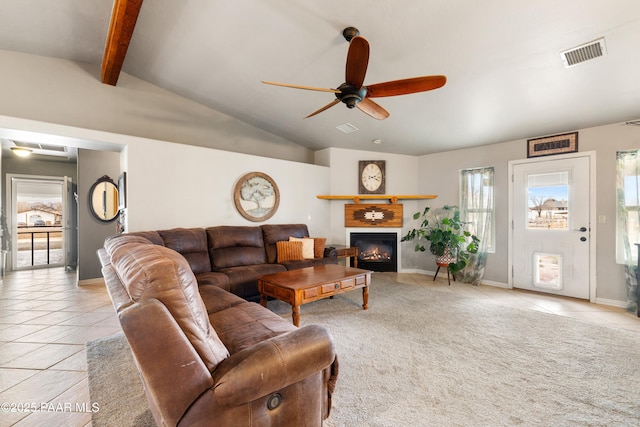 living room featuring visible vents, vaulted ceiling with beams, ceiling fan, light tile patterned floors, and a glass covered fireplace