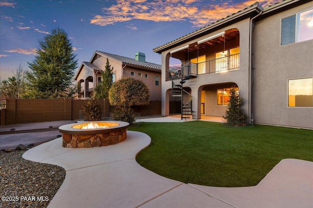 exterior space with a patio, a balcony, a yard, and a fire pit