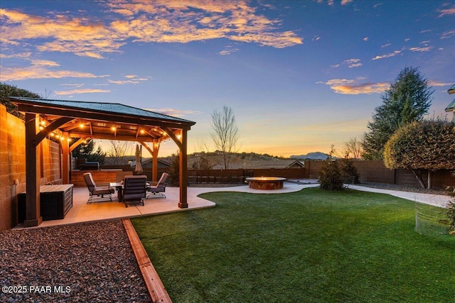 yard at dusk with a gazebo, a patio area, a hot tub, and an outdoor fire pit