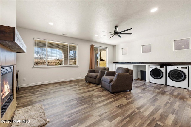 living room with wood-type flooring, ceiling fan, washing machine and clothes dryer, and a textured ceiling