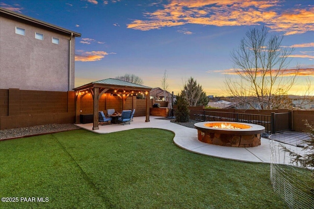 yard at dusk featuring a gazebo, a patio area, and a fire pit