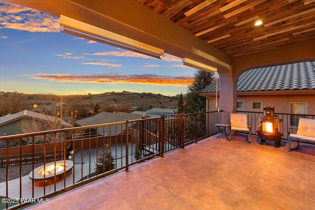 balcony at dusk featuring a fire pit