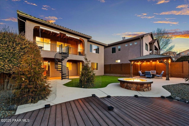 deck at dusk with a gazebo, a patio area, and an outdoor fire pit