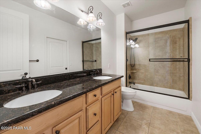 full bathroom featuring tile patterned flooring, bath / shower combo with glass door, vanity, and toilet