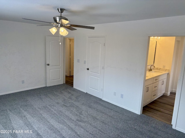 unfurnished bedroom with dark colored carpet, sink, connected bathroom, and ceiling fan