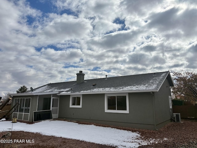 snow covered house with a sunroom and central air condition unit