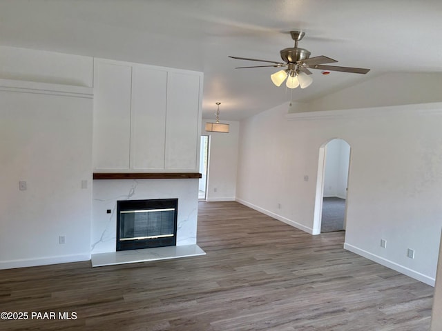 unfurnished living room with ceiling fan, a high end fireplace, vaulted ceiling, and light hardwood / wood-style flooring