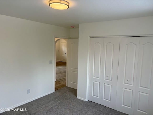 unfurnished bedroom with a closet and dark colored carpet