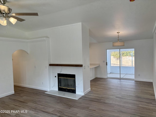 unfurnished living room featuring ceiling fan, a high end fireplace, dark hardwood / wood-style floors, and lofted ceiling