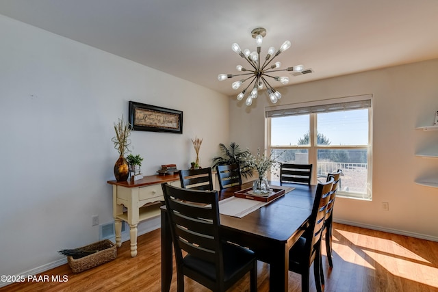 dining space with baseboards, wood finished floors, visible vents, and a chandelier