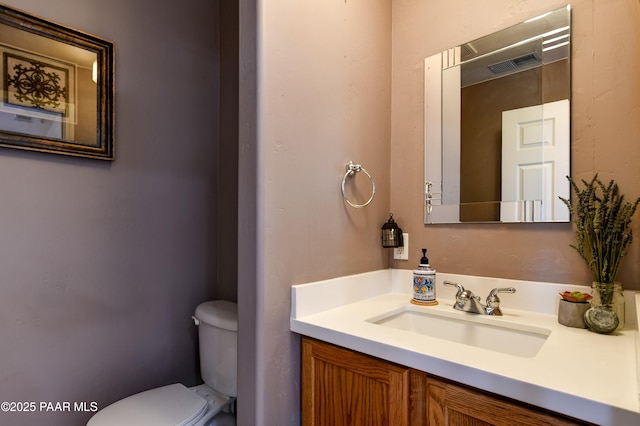 bathroom featuring vanity, toilet, and visible vents