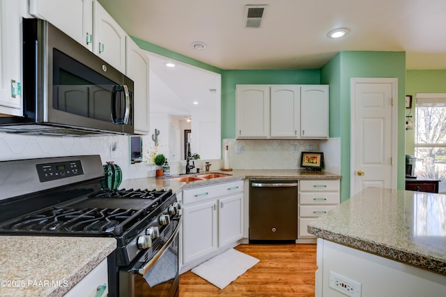 kitchen with tasteful backsplash, visible vents, stainless steel appliances, white cabinetry, and a sink