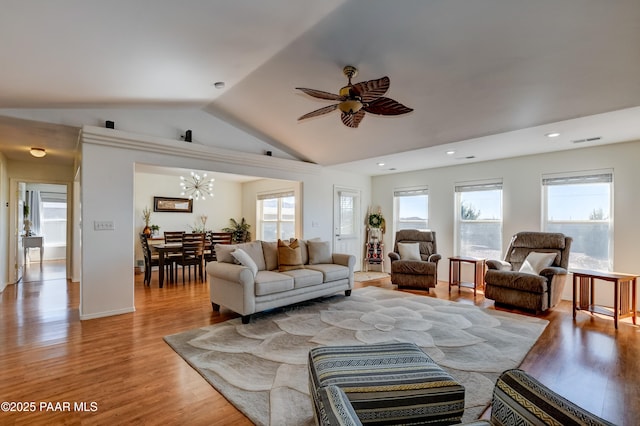 living area with lofted ceiling, ceiling fan with notable chandelier, visible vents, and light wood finished floors