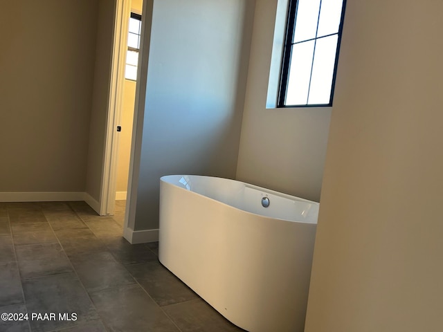 bathroom featuring tile patterned flooring, a tub, and a wealth of natural light