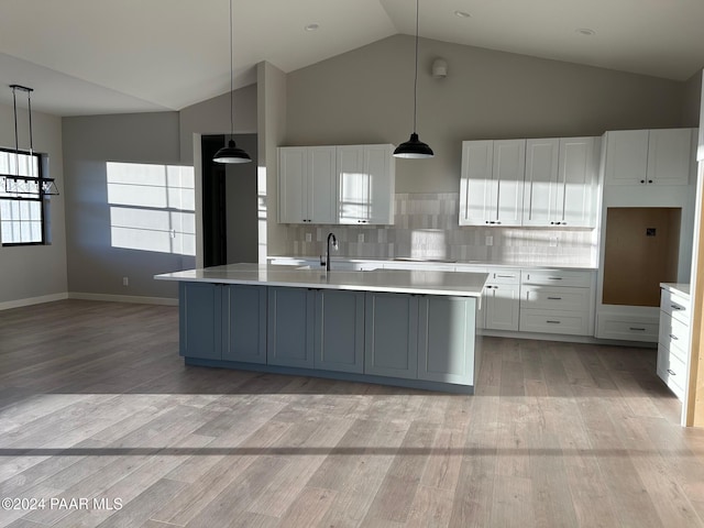 kitchen with white cabinetry, hanging light fixtures, and an island with sink