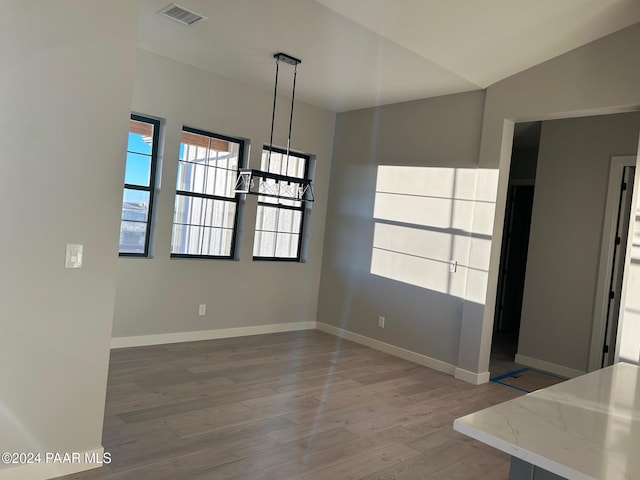 unfurnished dining area featuring lofted ceiling and wood-type flooring