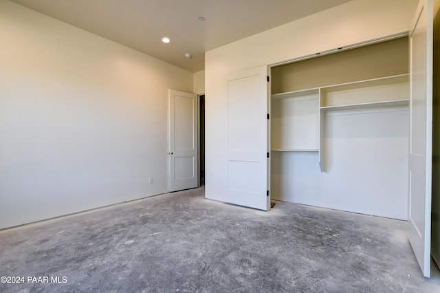 unfurnished bedroom with a closet and concrete floors