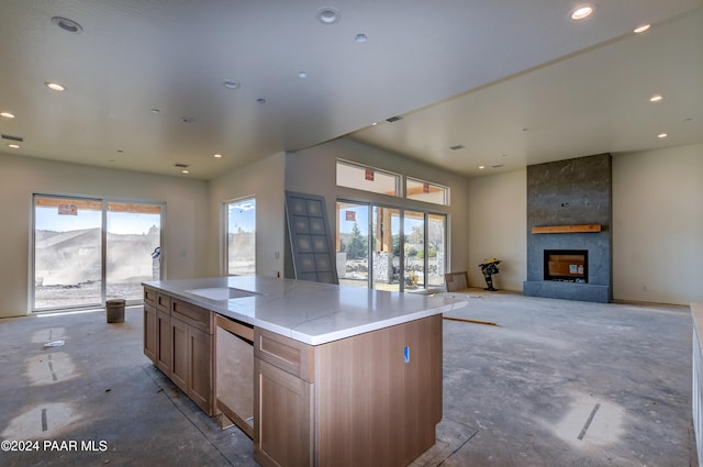 kitchen featuring a large fireplace, white cooktop, a healthy amount of sunlight, and a kitchen island