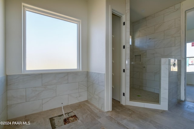 bathroom with a tile shower and tile walls