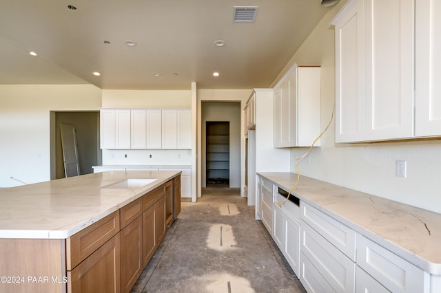 kitchen featuring white cabinets, a spacious island, and light stone countertops