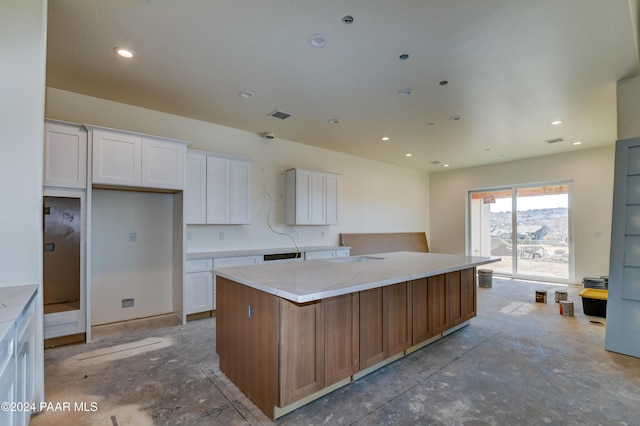 kitchen with white cabinets, a kitchen island, and light stone counters