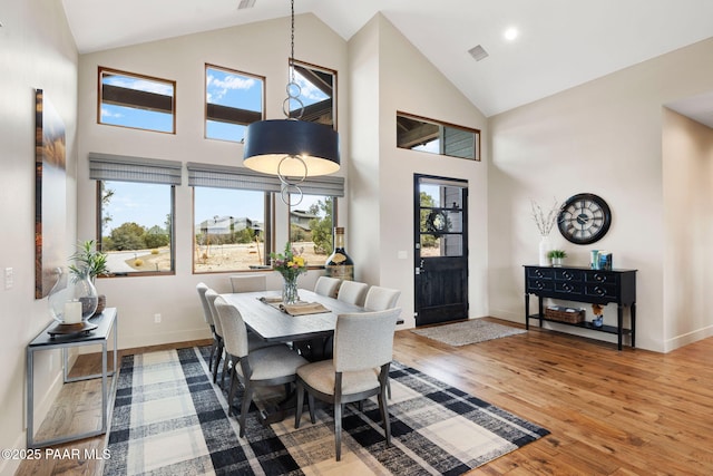 dining space with a wealth of natural light, visible vents, high vaulted ceiling, and wood finished floors