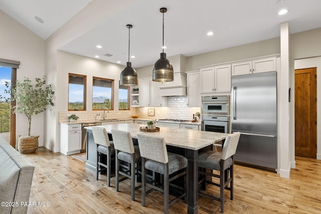 kitchen featuring a sink, tasteful backsplash, a center island, stainless steel appliances, and white cabinets