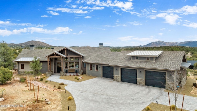 view of front facade with a mountain view, stone siding, an attached garage, and decorative driveway