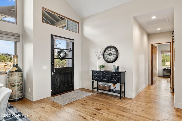 entryway with light wood-style flooring, high vaulted ceiling, and baseboards