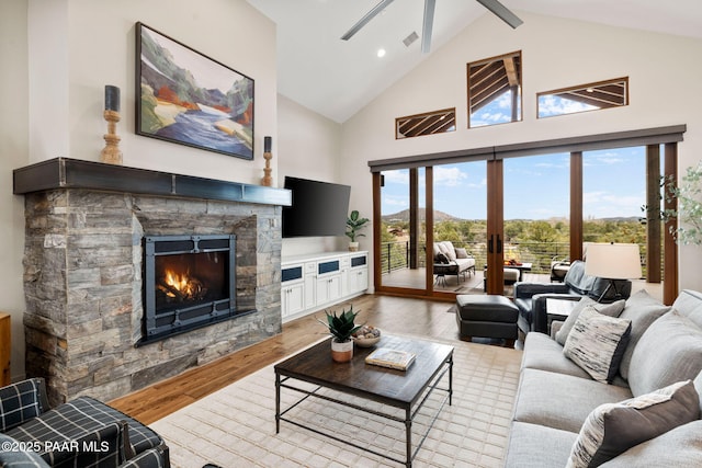 living area featuring beamed ceiling, visible vents, high vaulted ceiling, wood finished floors, and a stone fireplace