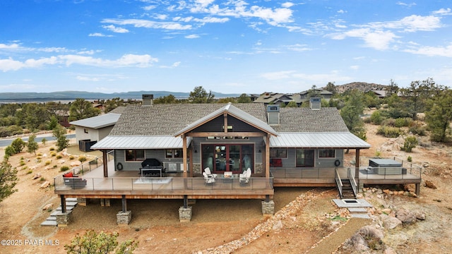 back of house featuring a standing seam roof, a deck with mountain view, and metal roof