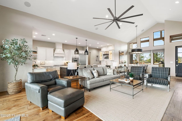 living room with recessed lighting, high vaulted ceiling, ceiling fan, and light wood finished floors