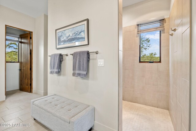 full bathroom featuring tiled shower and baseboards