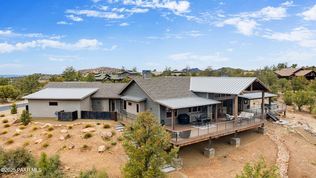 rear view of house with a wooden deck, a standing seam roof, and metal roof