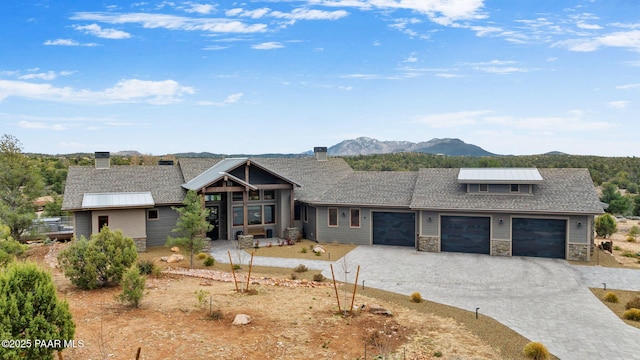 view of front of home with stone siding, a mountain view, an attached garage, and decorative driveway