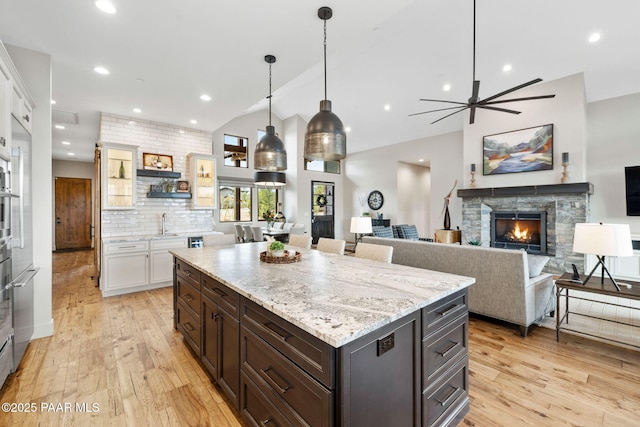 kitchen with decorative backsplash, recessed lighting, a fireplace, light wood-style flooring, and white cabinets