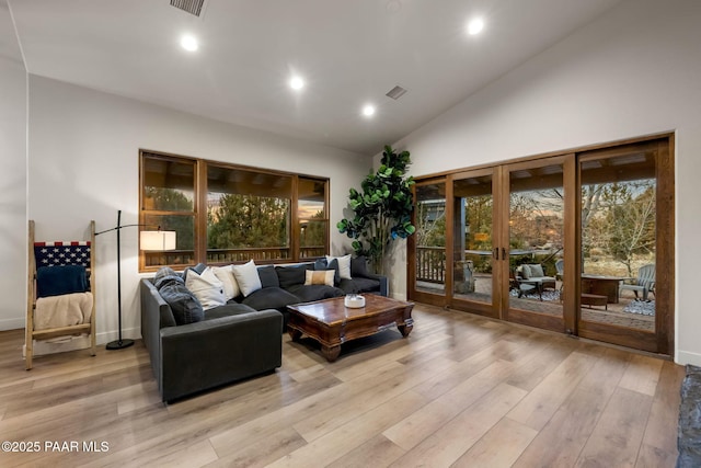 living room featuring high vaulted ceiling, french doors, and light wood-type flooring