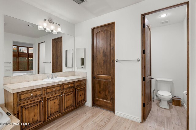 bathroom featuring toilet, hardwood / wood-style floors, and vanity