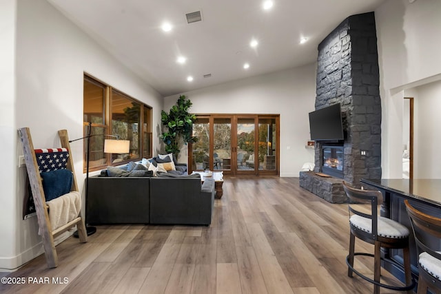 living room featuring a healthy amount of sunlight, a fireplace, light hardwood / wood-style flooring, and high vaulted ceiling