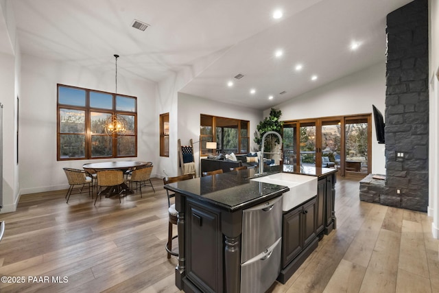 kitchen featuring decorative light fixtures, french doors, a kitchen breakfast bar, sink, and a center island with sink