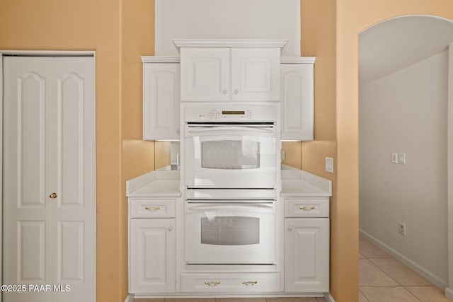 kitchen featuring double oven, white cabinets, light tile patterned flooring, and light countertops