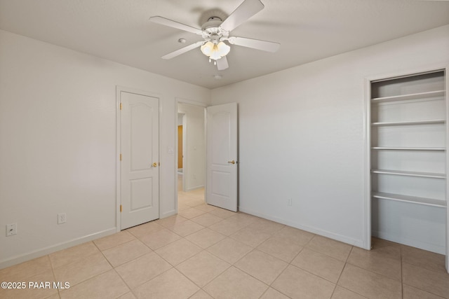 unfurnished bedroom featuring light tile patterned flooring, a ceiling fan, and baseboards